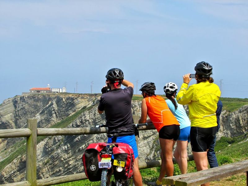 Cicloturistas en Oviñana cerca del Faro Vidio (al fondo)